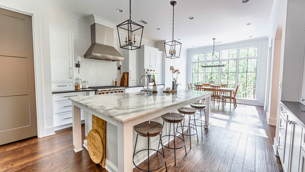 A modern kitchen featuring a sleek marble island with bar stools arranged around it.