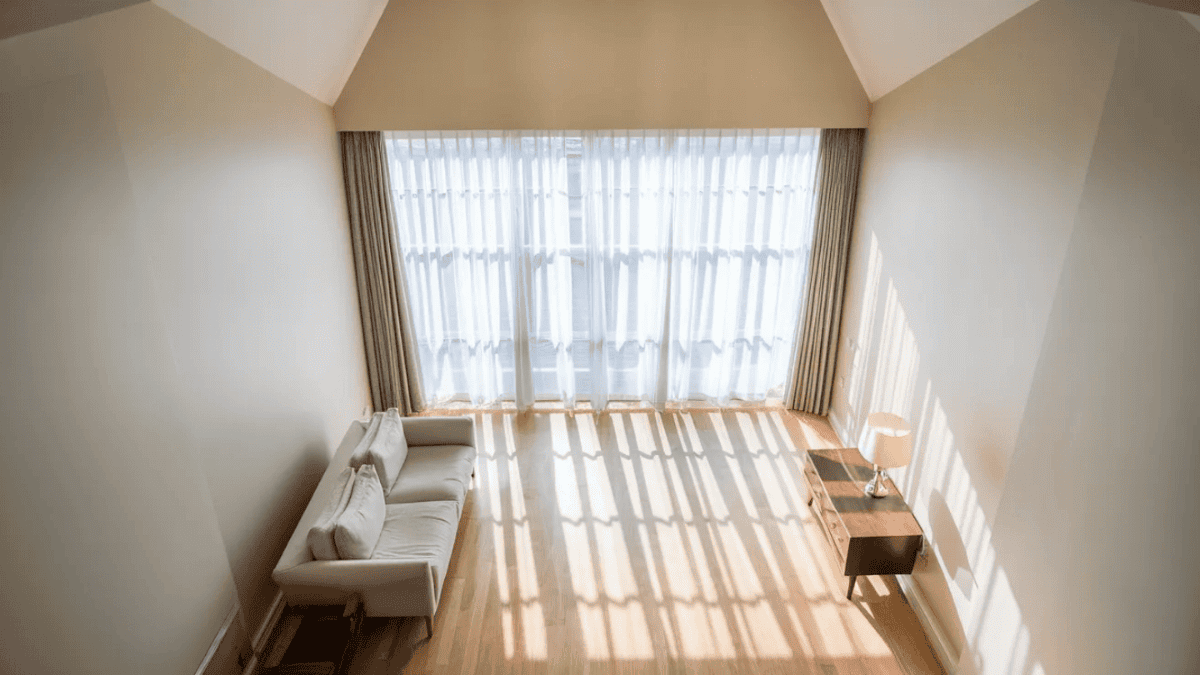 bright minimal living room with sheer window treatments and reflective surfaces maximizing natural daylight throughout