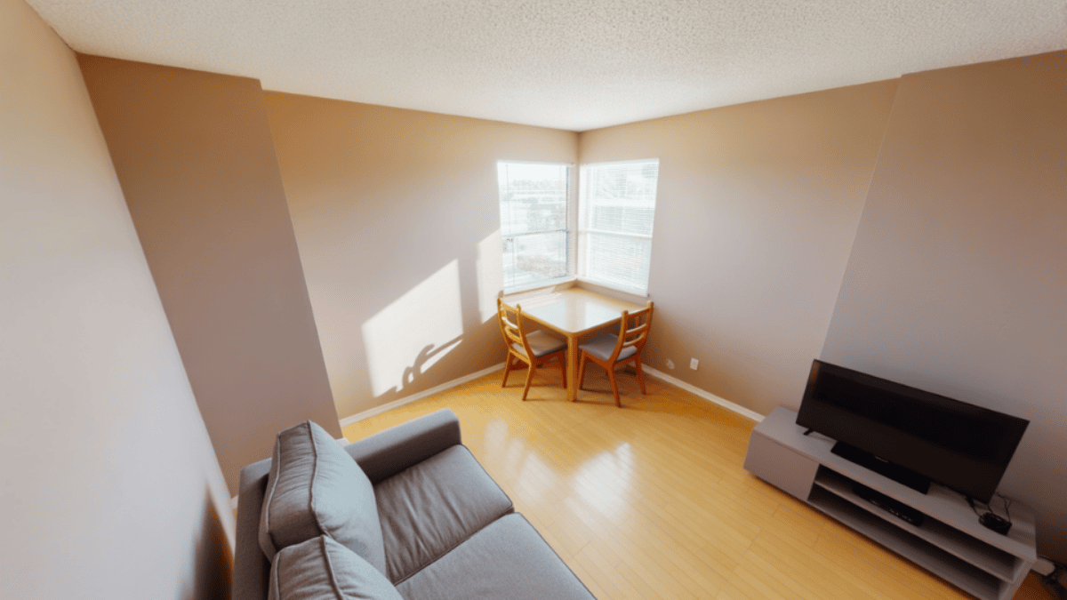 minimal open plan room with a small dining table tucked into a corner leaving the living area center completely open