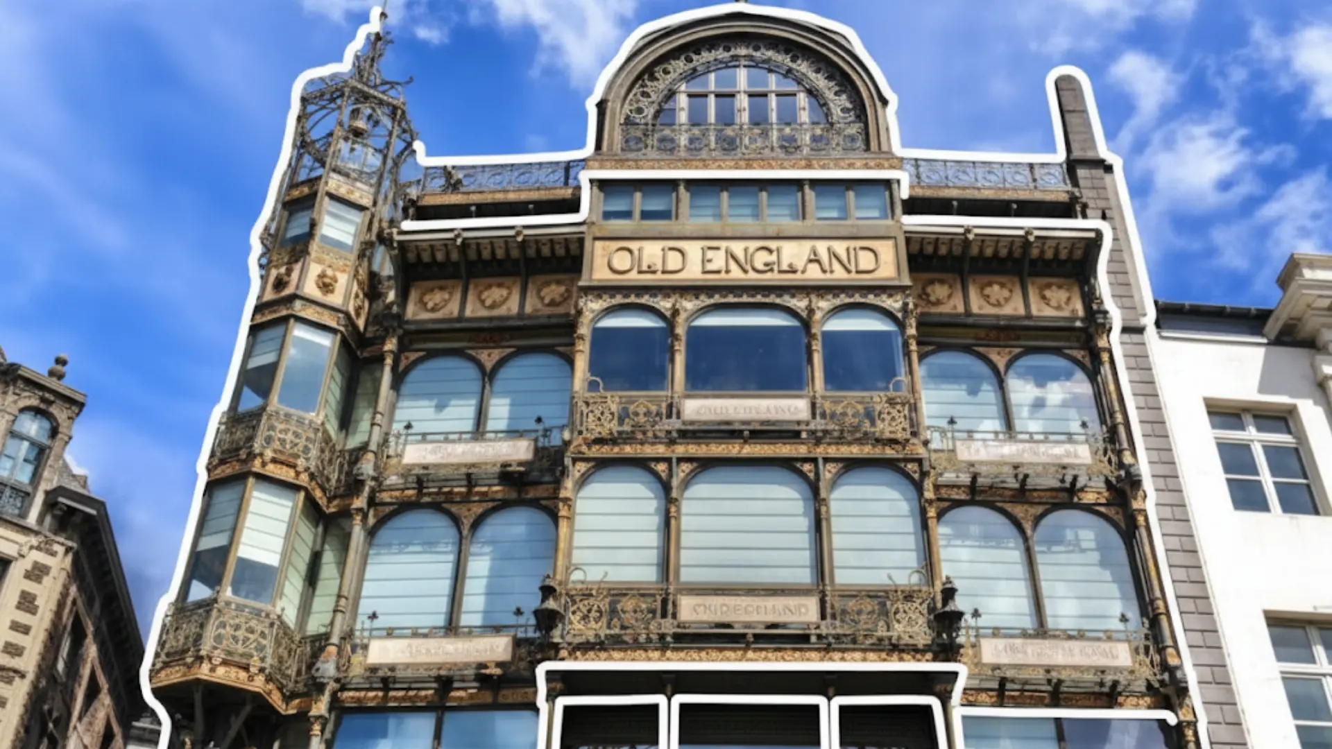 old england building brussels belgium highlights the black iron framework and glass panels of the arched storefront