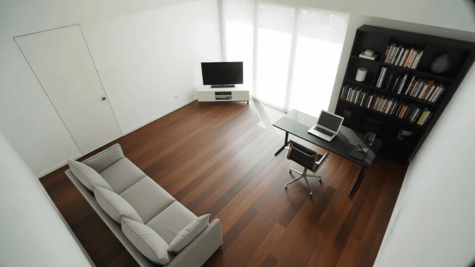 overhead view of a minimal living room with a sofa on one side and a desk and bookshelf on the other