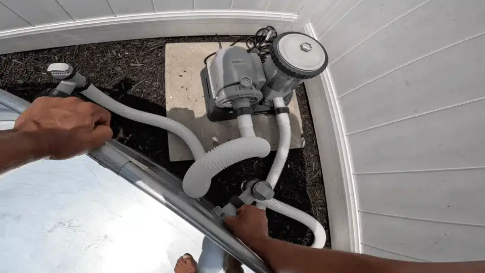 overhead view of connecting white hoses from an intex pool pump to the valves on the stock tank wall