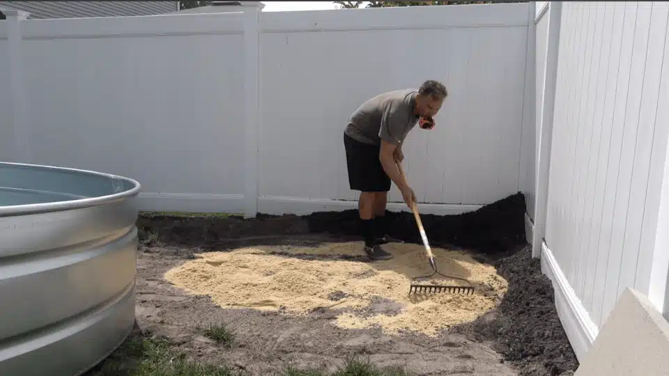 spreading leveling sand on ground to prepare base for stock tank pool