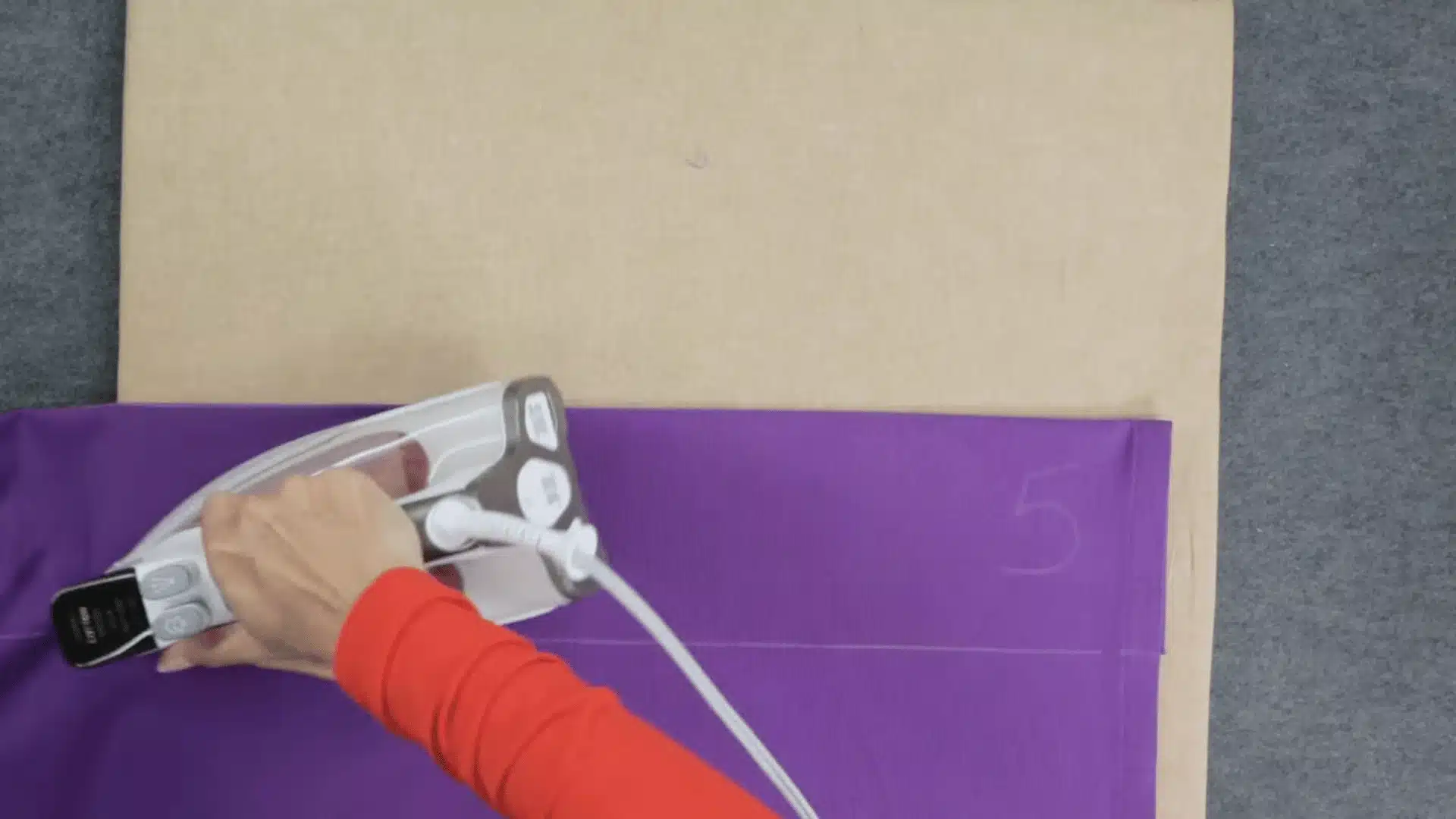 the photo showing the ironing of the purple curtains on the board in order to get sew
