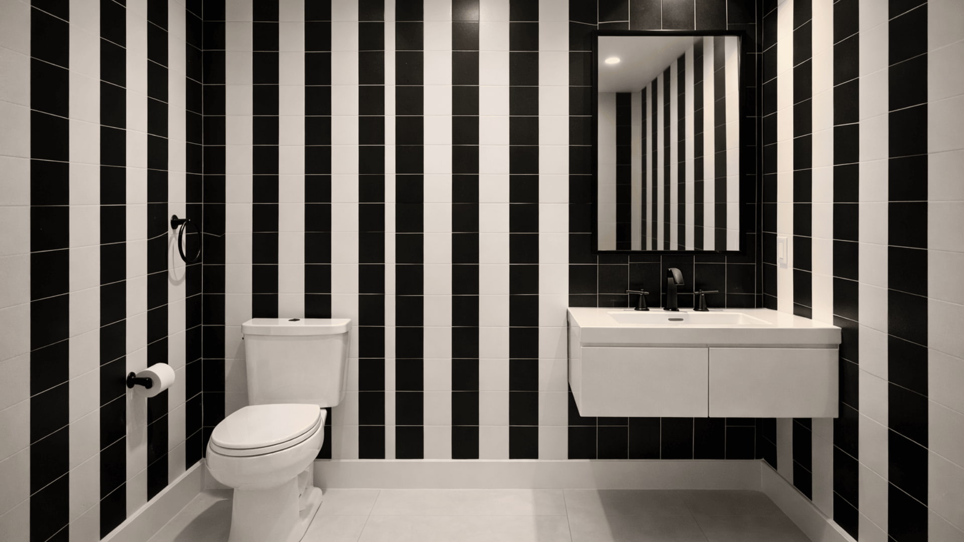 bathroom with black and white vertical striped tile walls, white vanity and matte black fixtures