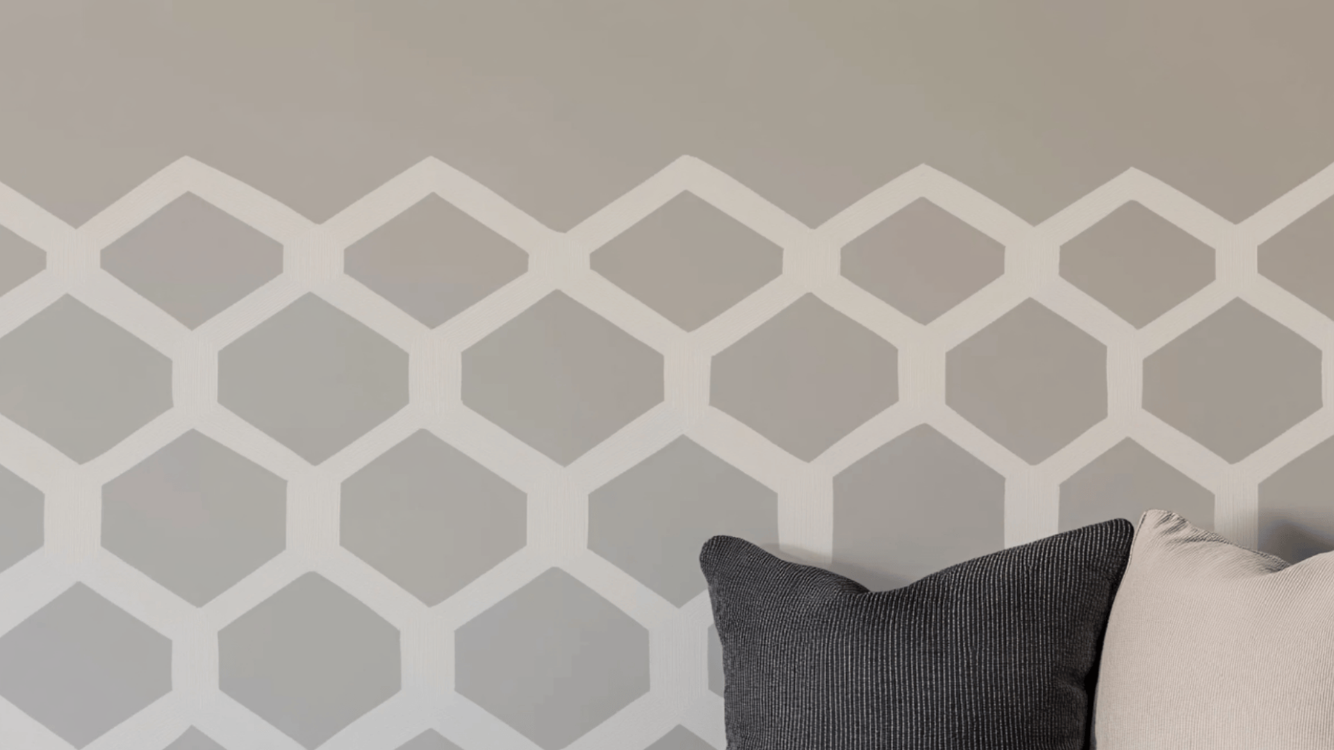 close-up of a wall painted in alpaca featuring a raised hexagonal stencil pattern with two decorative pillows