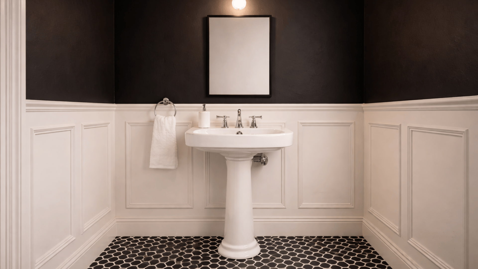 powder room with white paneled wainscoting, black upper walls, pedestal sink and single warm wall sconce