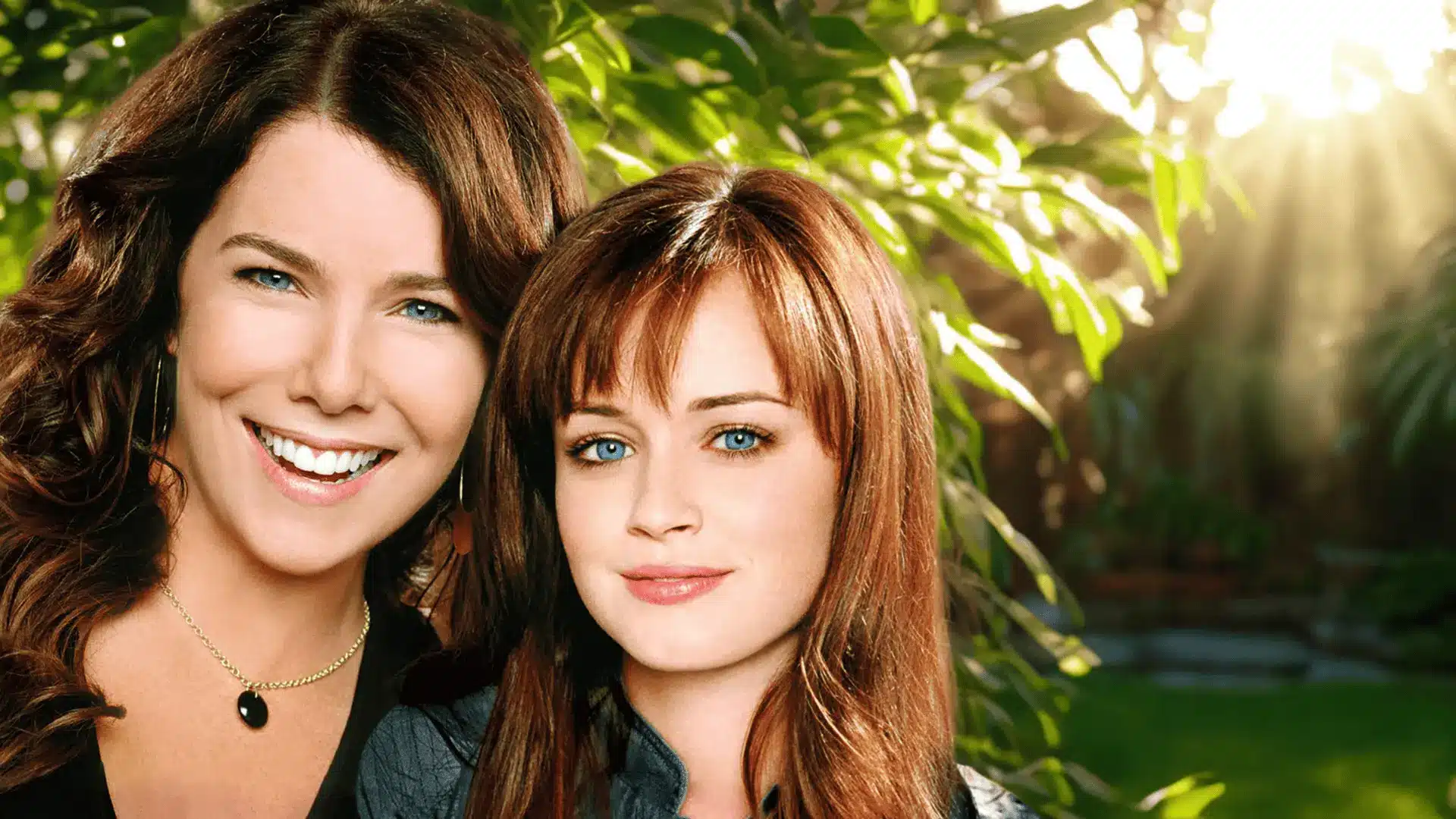 Two women standing close together outdoors with sunlight through green leaves in the background