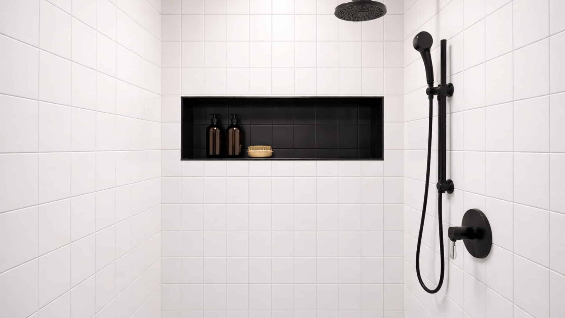 white shower with black recessed niche, matte black rainfall showerhead and handheld fixtures on white tile