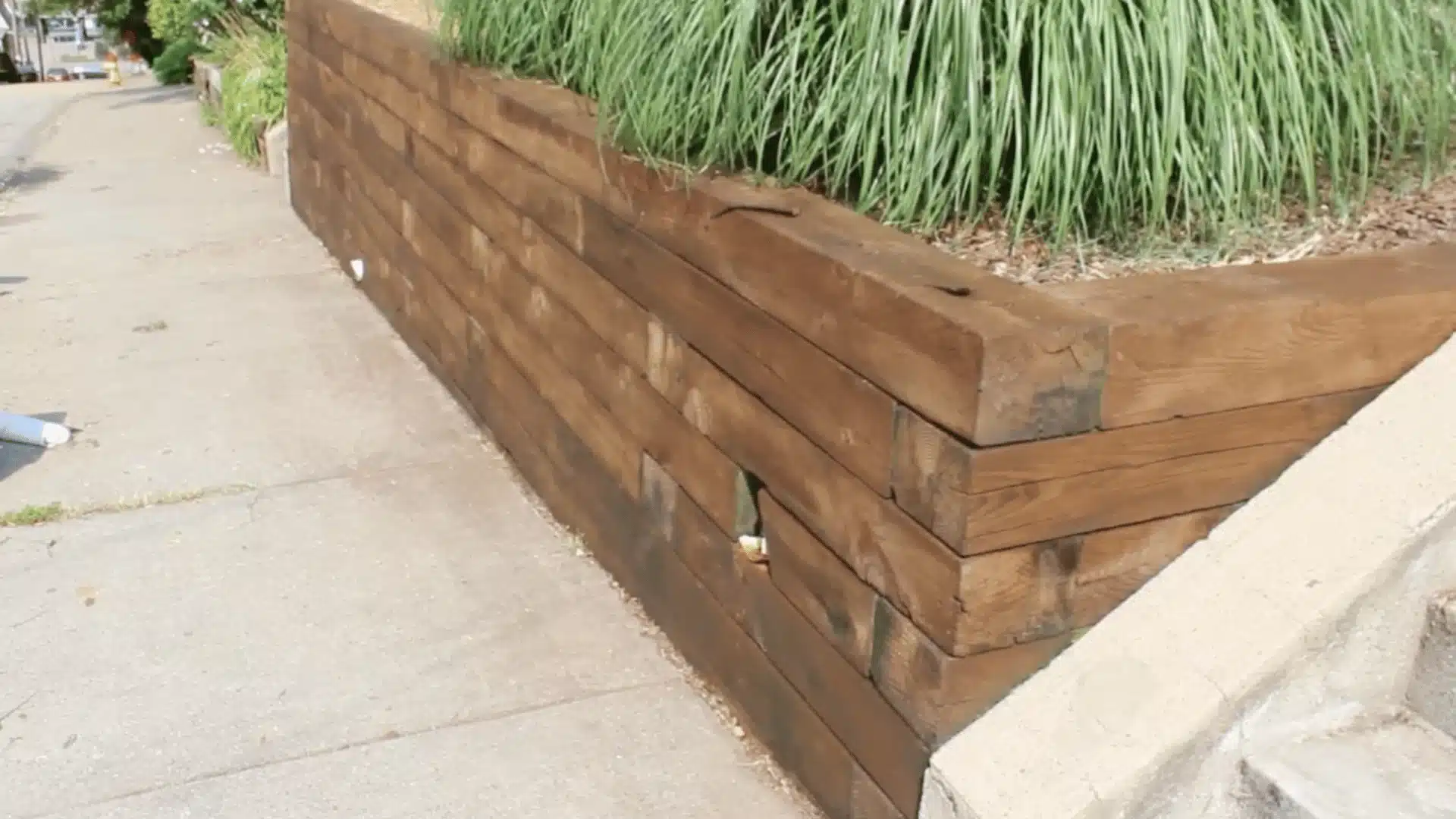 a close-up photograph of a wooden retaining wall made from horizontal wooden planks