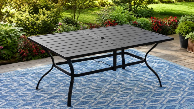 A metal table with slatted top stands on a blue geometric-patterned rug