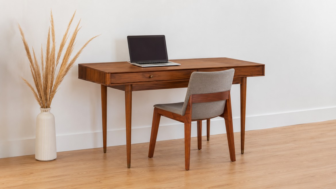 A minimalist workspace featuring a work desk with a laptop, a mid-century modern chair