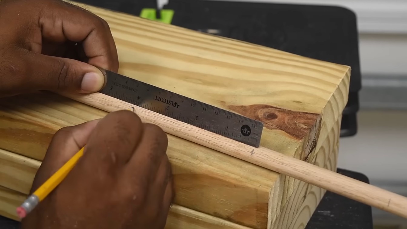 a person measures a wooden dowel with a metal ruler on top of stacked wooden planks