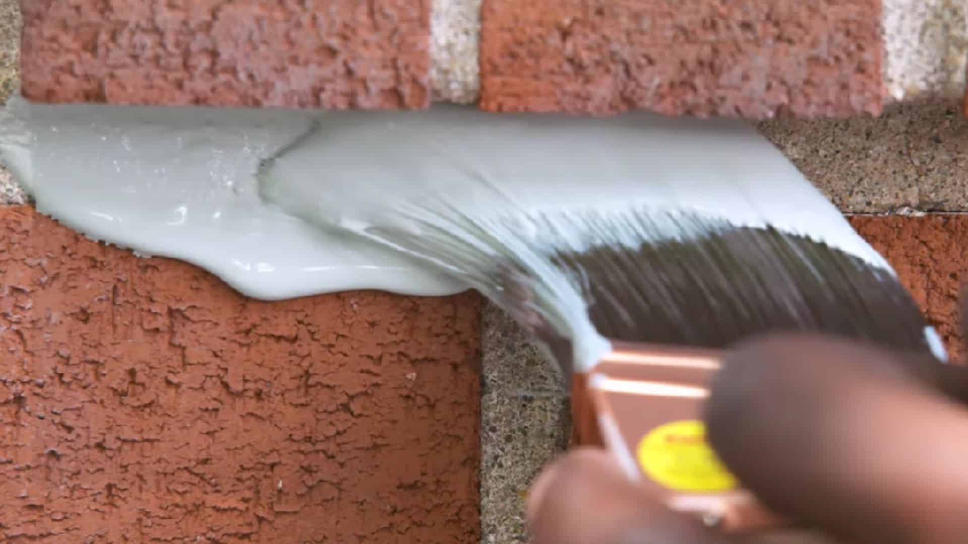 applying paint on brick wall using roller and brush for full coverage