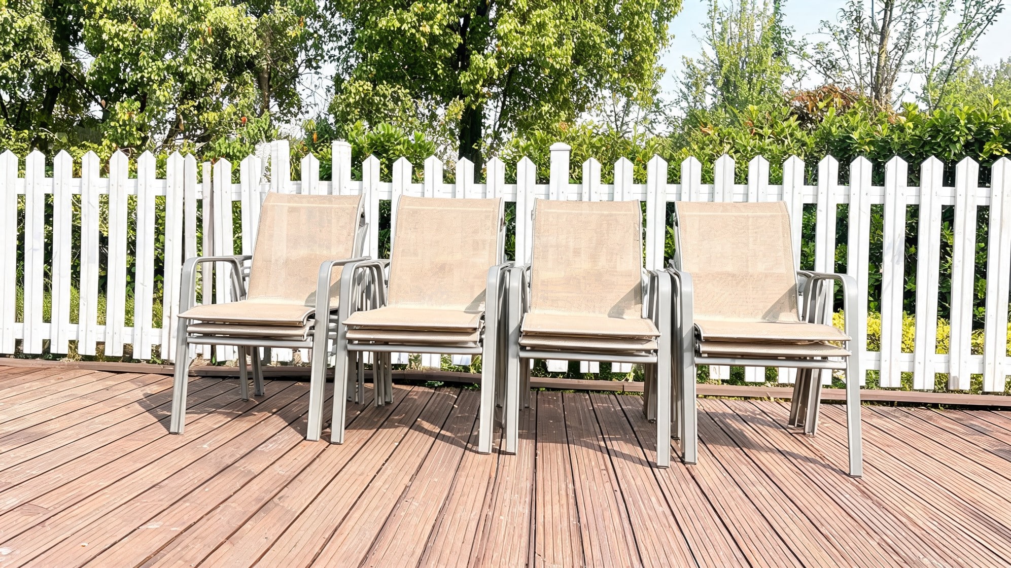 Stacked beige patio chairs on a wooden deck