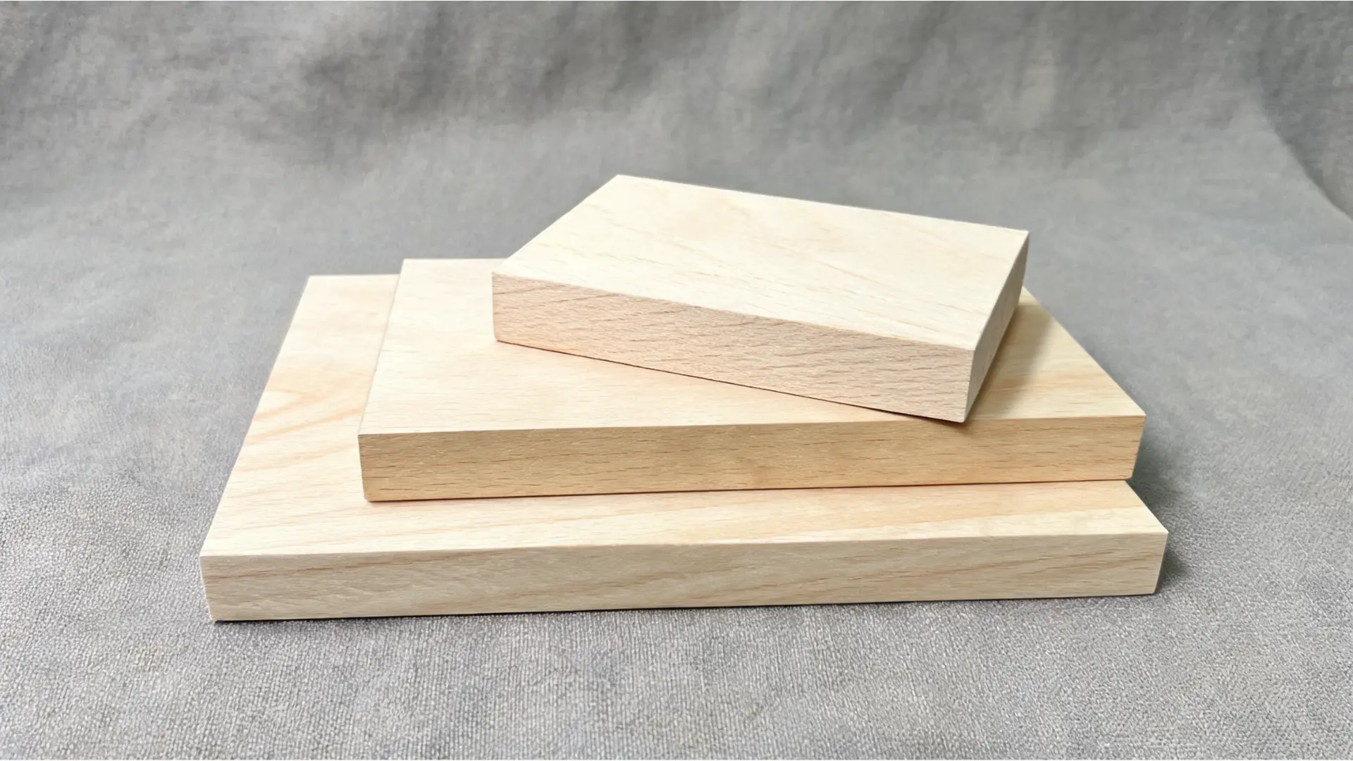 stacked basswood boards with smooth pale grain on a gray fabric background for craft and acrylic painting projects