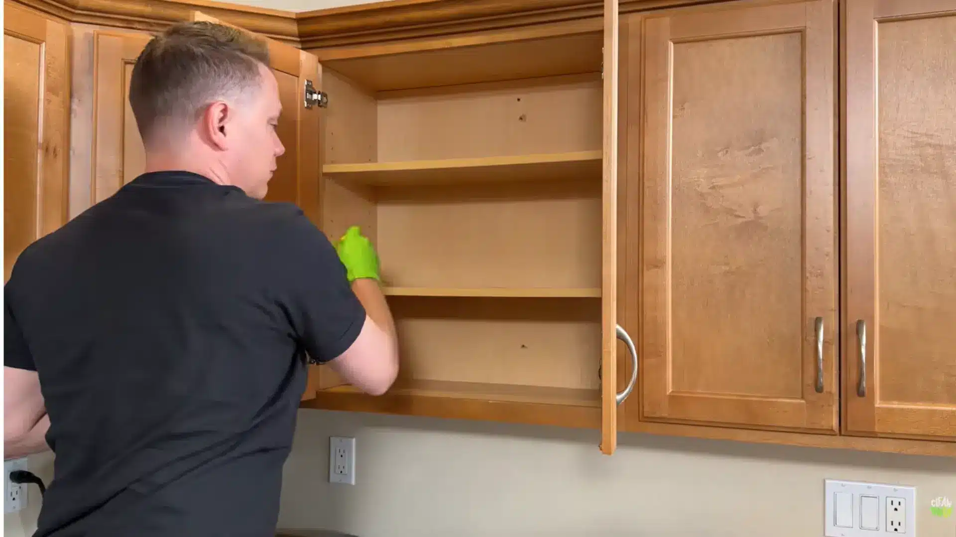 person cleaning inside empty wood cabinets one section at a time during a deep kitchen cabinet clean