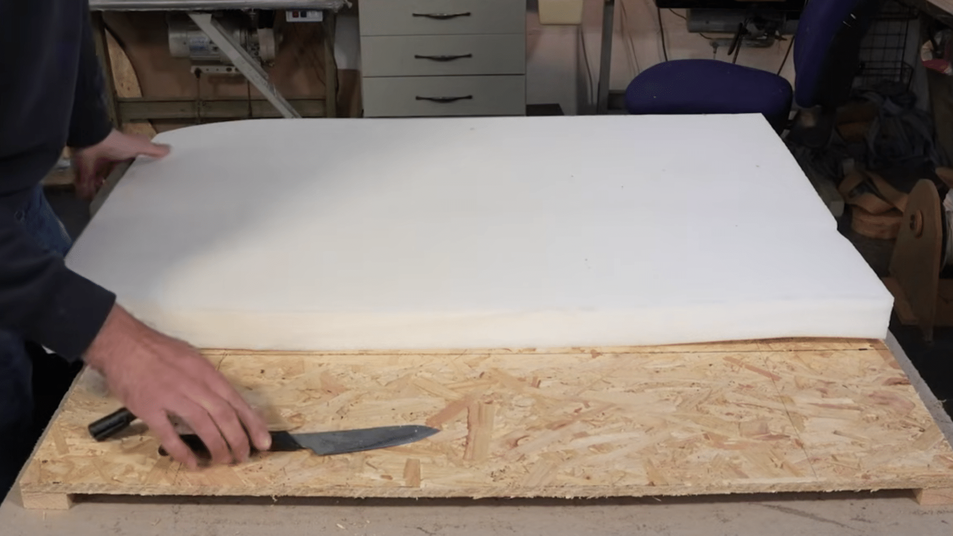 cutting upholstery foam and gluing it onto wooden headboard base with spray adhesive