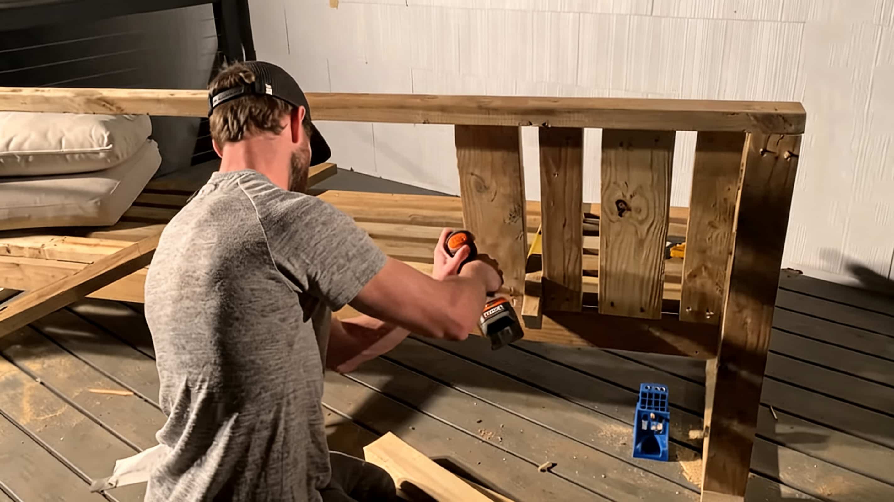 person attaching angled wooden backrest boards to an outdoor sectional frame with a drill on a deck