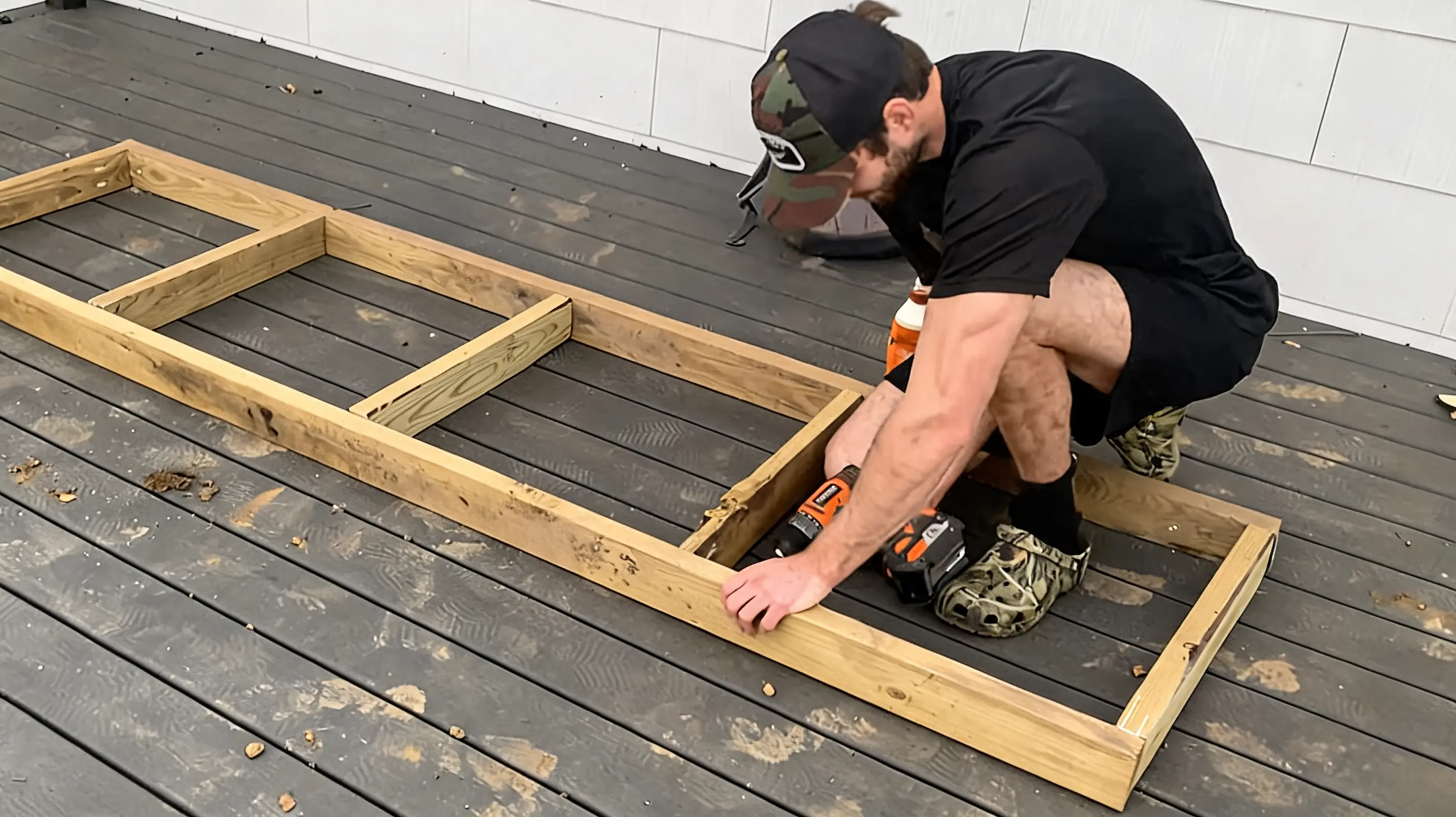 person fastening wooden braces inside an outdoor sectional frame on a dark deck