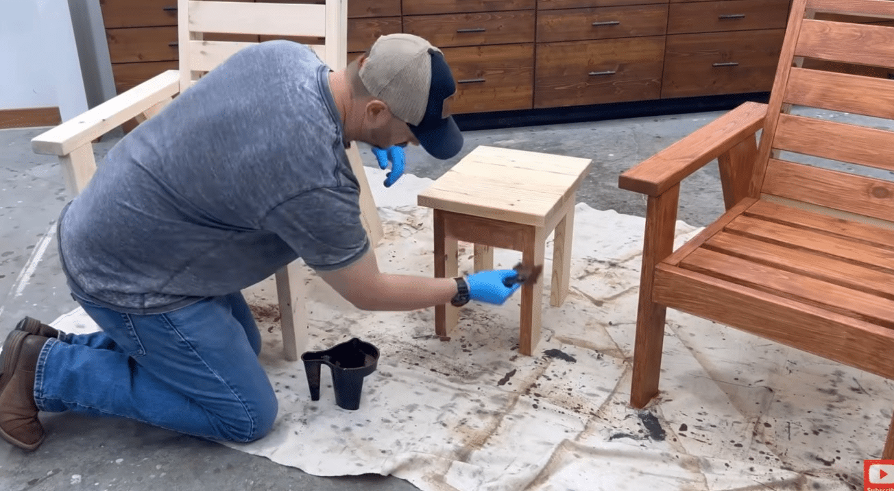 diy outdoor furniture staining process on a finished wooden patio chair and table set outdoors on concrete
