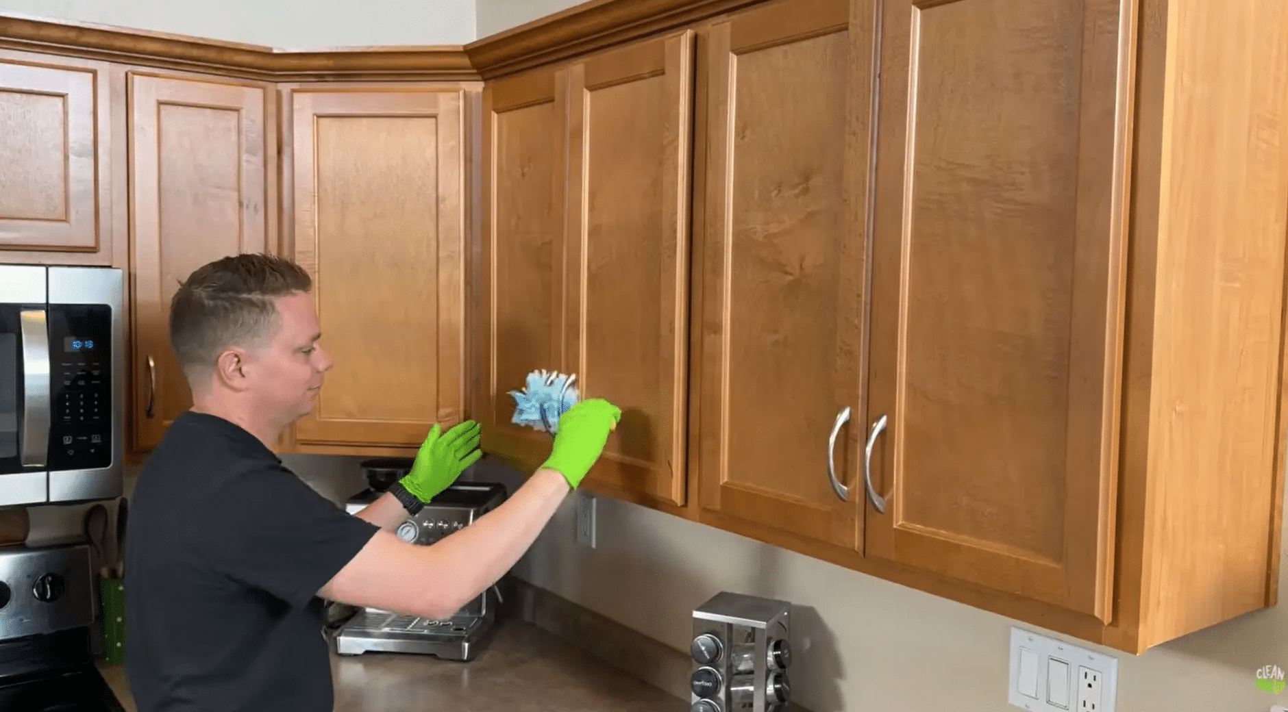 person dusting wooden kitchen cabinets before deep cleaning to remove grease, grime, and buildup