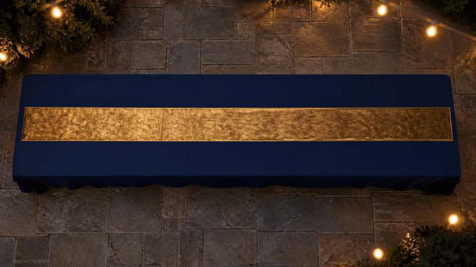 long table with deep navy cloth and gold runner on patio at dusk soft lights blurred background