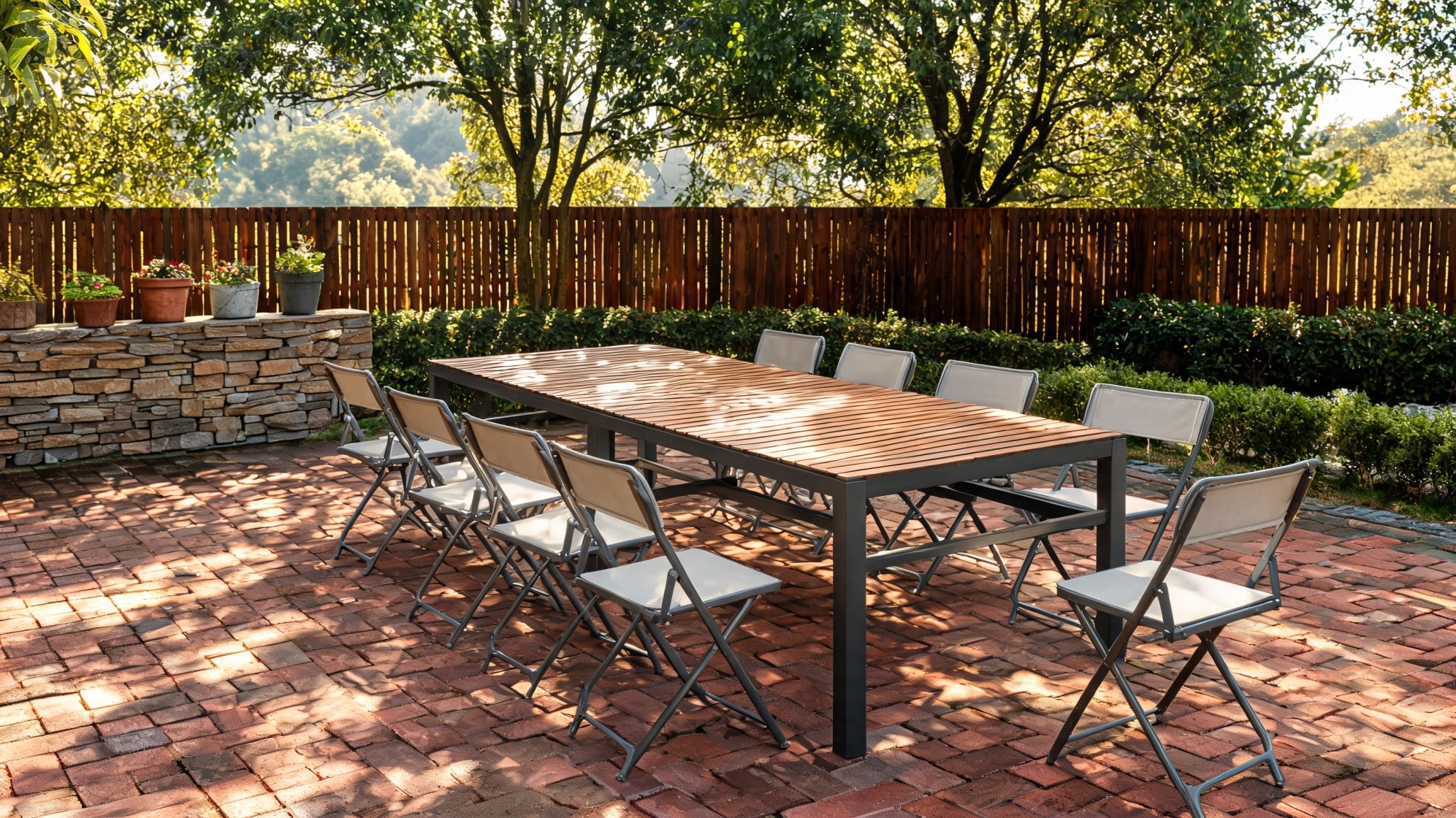 Long wooden outdoor dining table surrounded by eight folding chairs