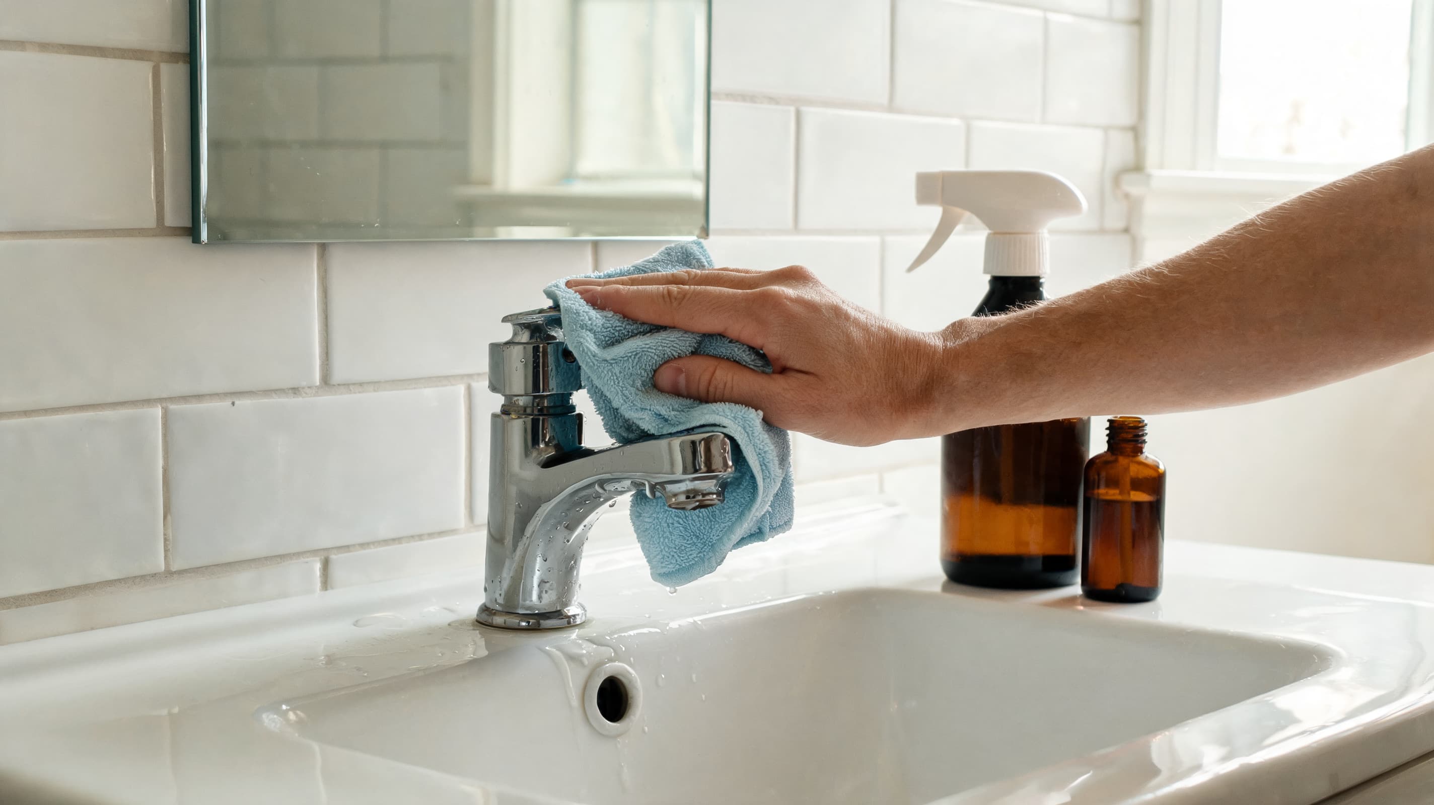 Person cleaning bathroom sink with hydrogen peroxide spray