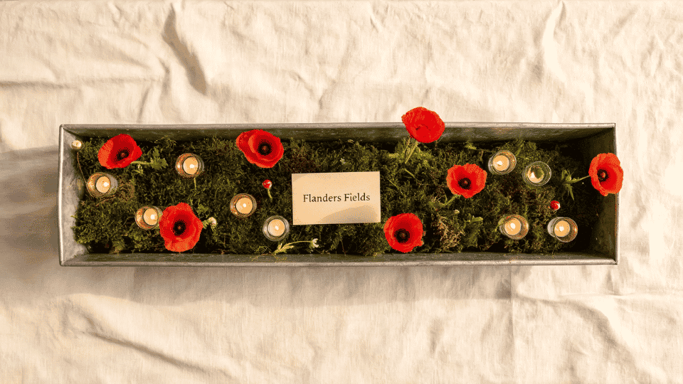 table centerpiece with moss red poppies and candles on linen dining table