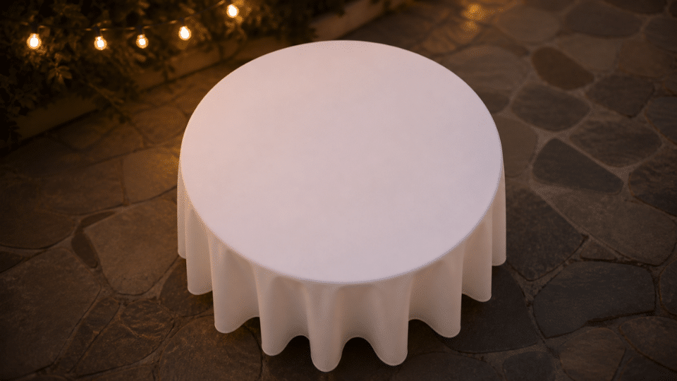 top down round table with plain white cloth on patio at dusk soft lights blurred background
