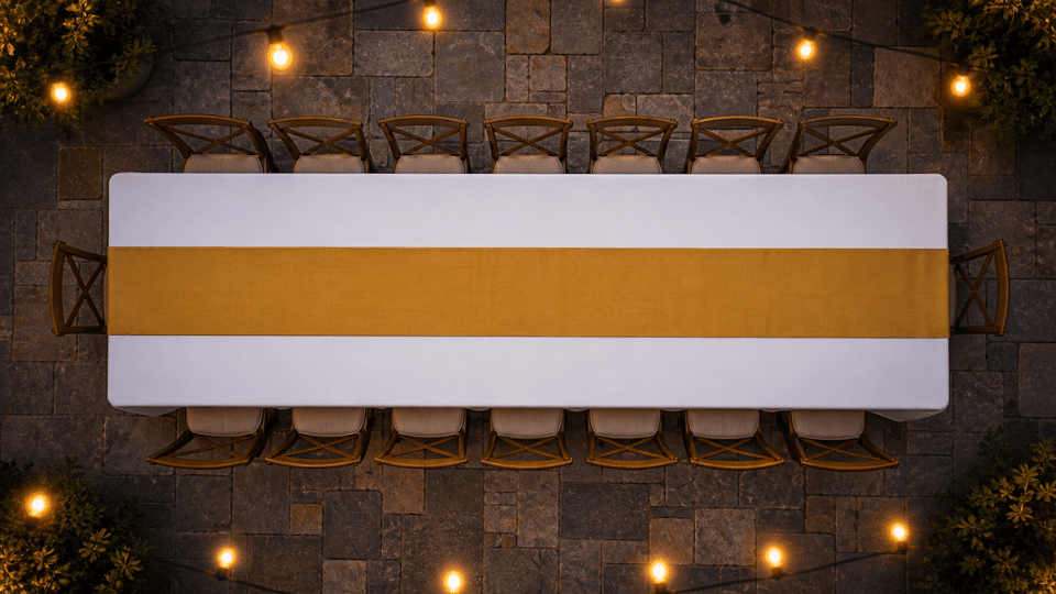 white tablecloth with deep gold runner on patio table at dusk soft lights blurred top down