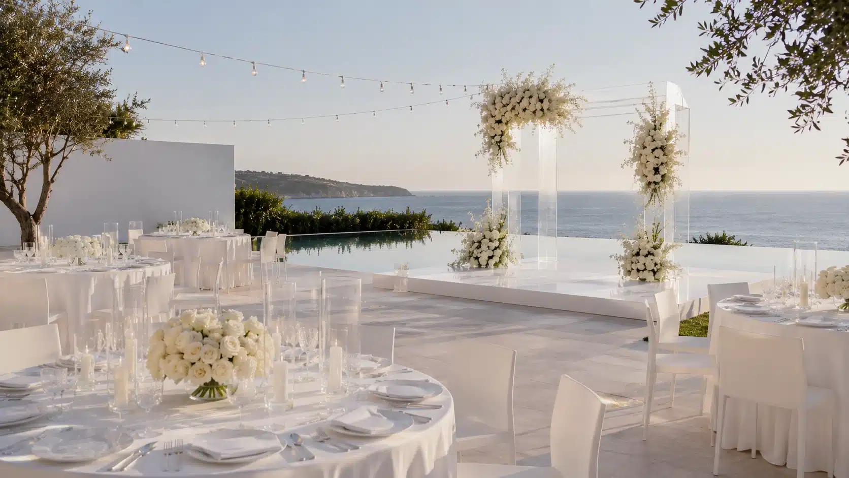 a modern outdoor wedding on a seaside terrace with white tables, chairs, a floral arch, perfect outdoor wedding ideas