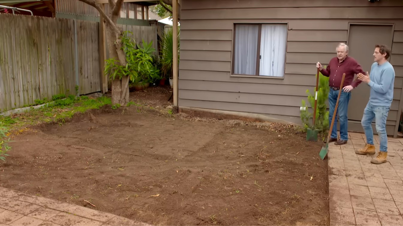 bare backyard soil area beside fence and house, ready for garden landscaping and new planting