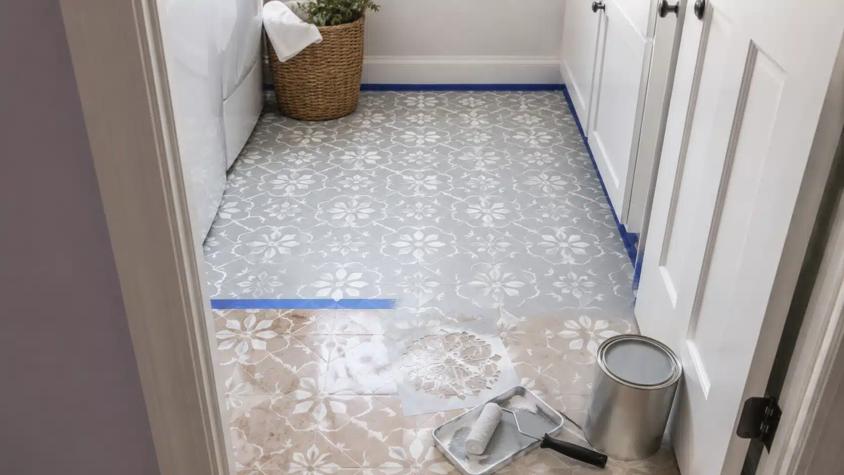 bathroom floor stencil painting for diy home projects, with gray paint, roller, blue tape, and patterned tile design