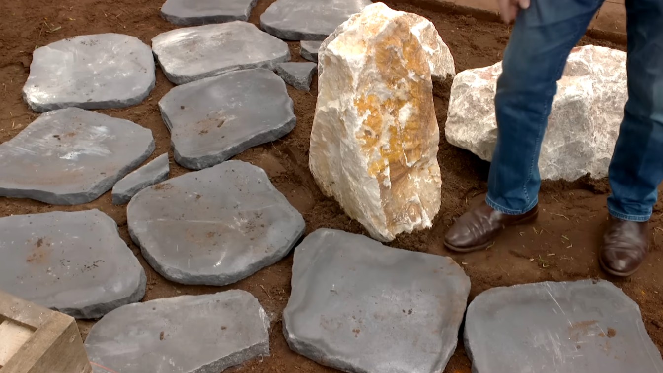 close up of natural stepping stones and large garden rocks being placed for a backyard path