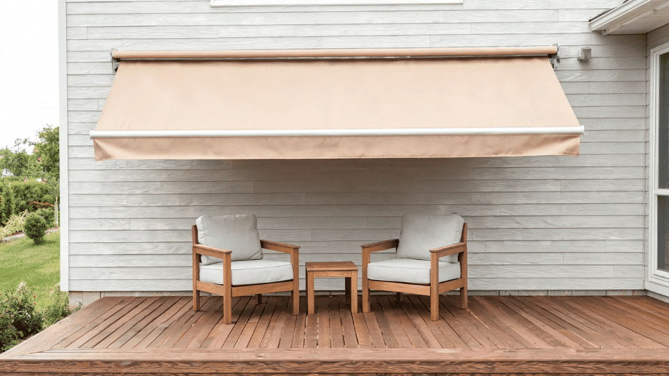 covered deck ideas on a budget with shaded chairs beneath a manual awning on a sunny wood deck area
