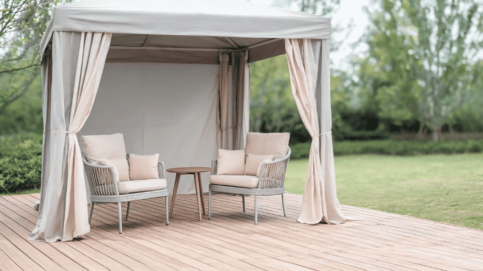 covered deck ideas on a budget with chairs in soft shade behind outdoor curtains on a wood deck