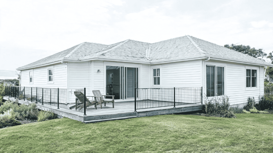 deck color ideas with driftwood gray boards and black railings on a white coastal style house view