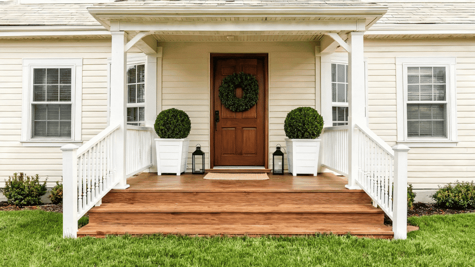 front porch decorating ideas with matching planters, lanterns, wreath, and classic entry
