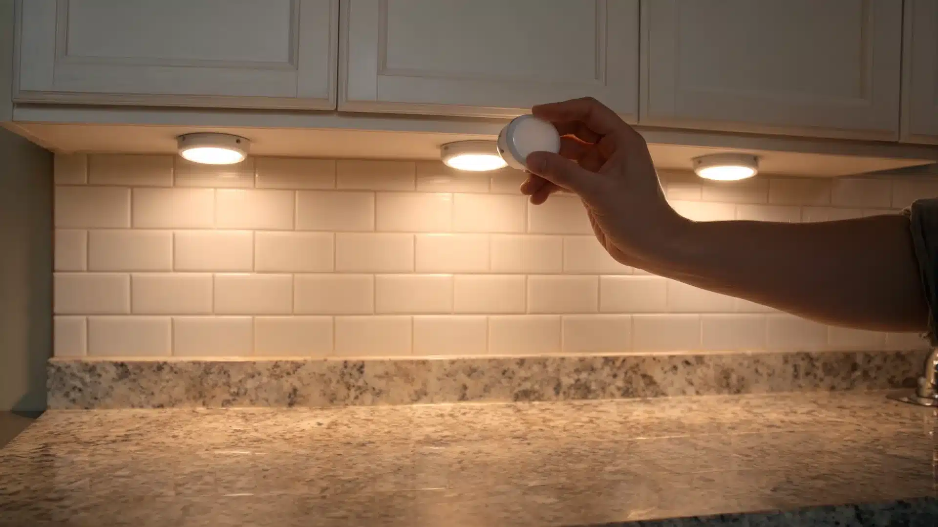 hand installing battery under-cabinet lights above a kitchen counter, a useful diy home projects lighting upgrade