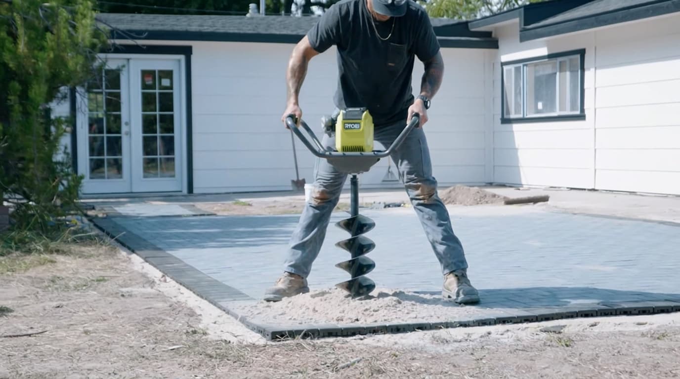 deep pergola footing holes being dug with an auger below the frost line in a patio area