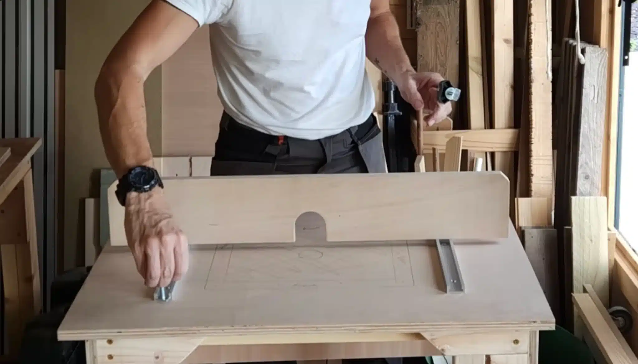 person adjusting router fence on diy router table for precise woodworking cuts in small workshop