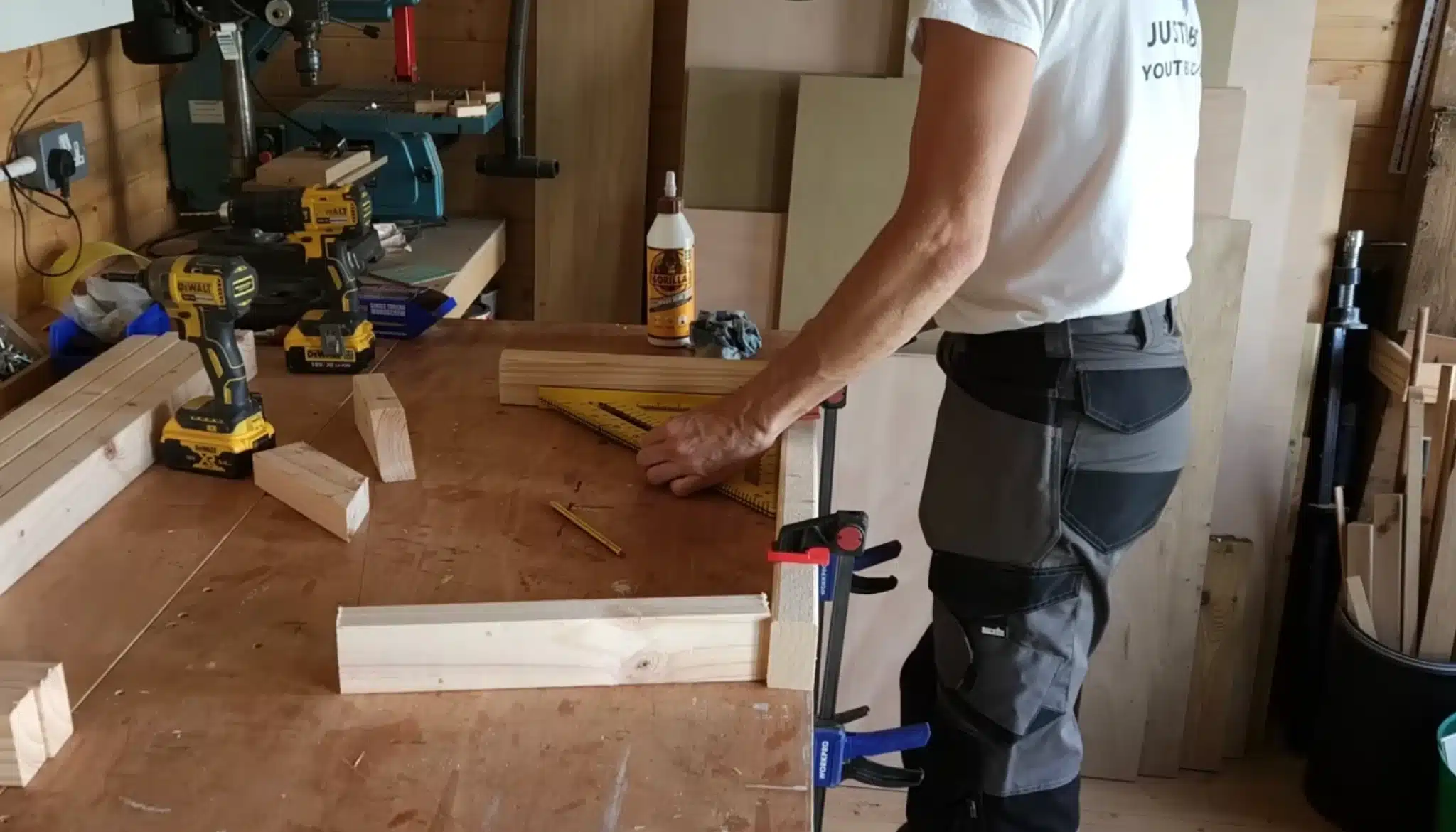 person measuring and marking wood for diy router table construction in workshop using square and clamps