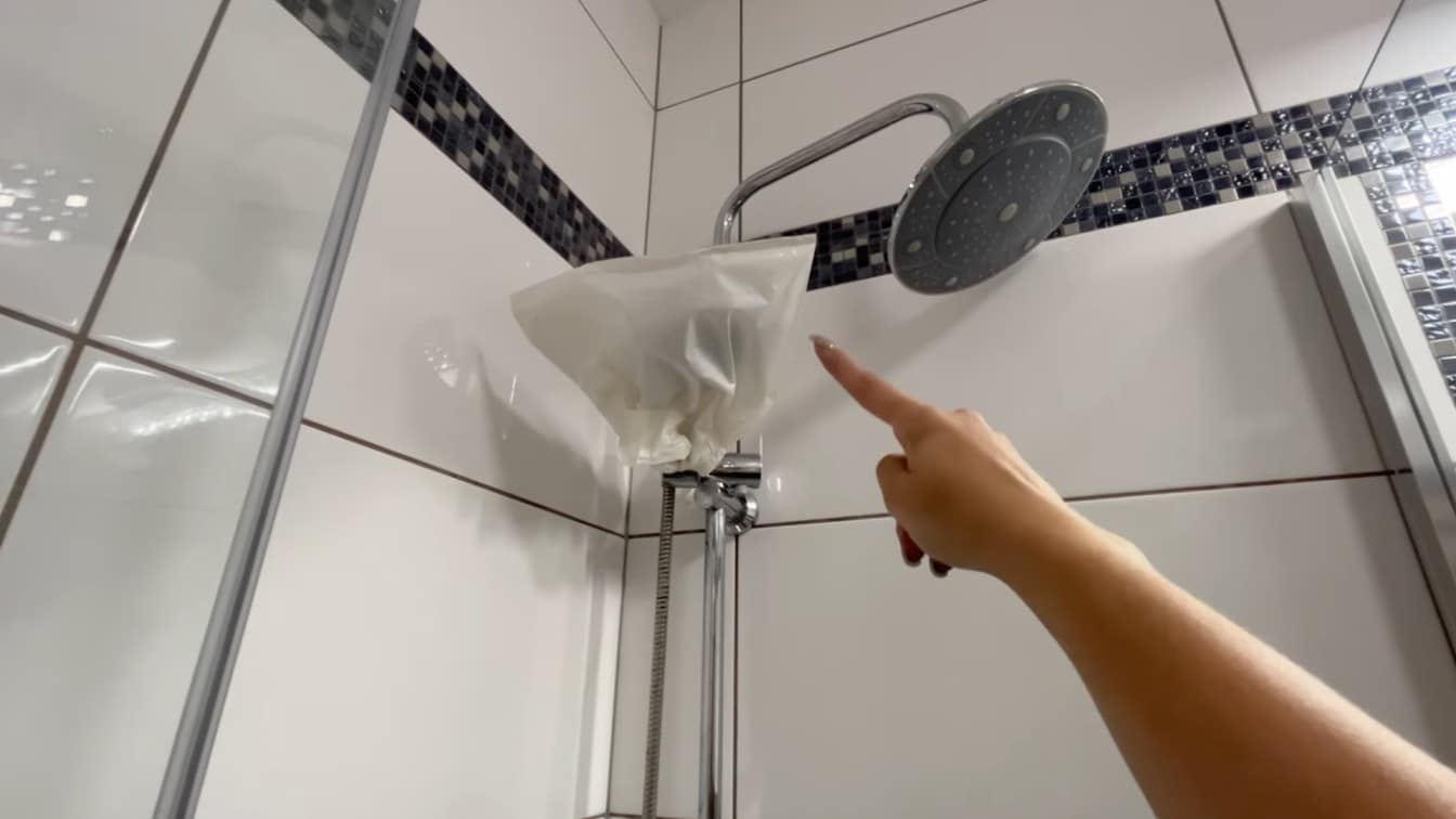 how to clean shower head by placing a vinegar filled plastic bag over the fixture to loosen buildup fast