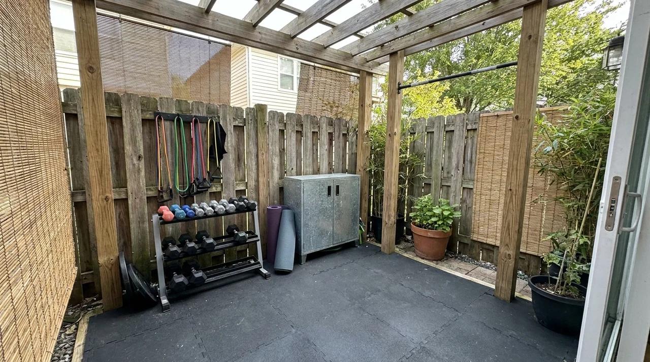 Compact backyard gym area with workout equipment and covered space.
