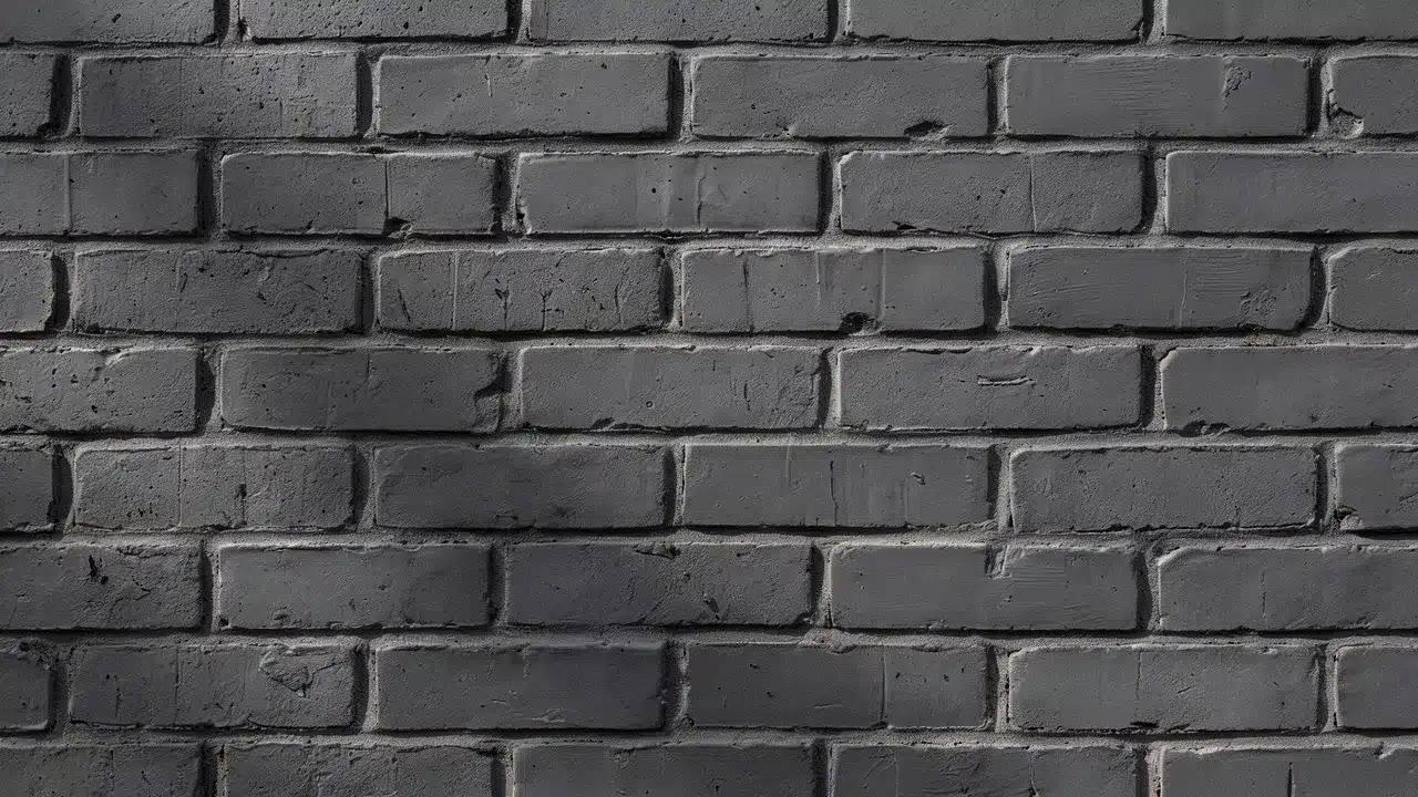 Charcoal gray brick stain creates a deep, modern finish while preserving the wall&rsquo;s rugged natural texture.