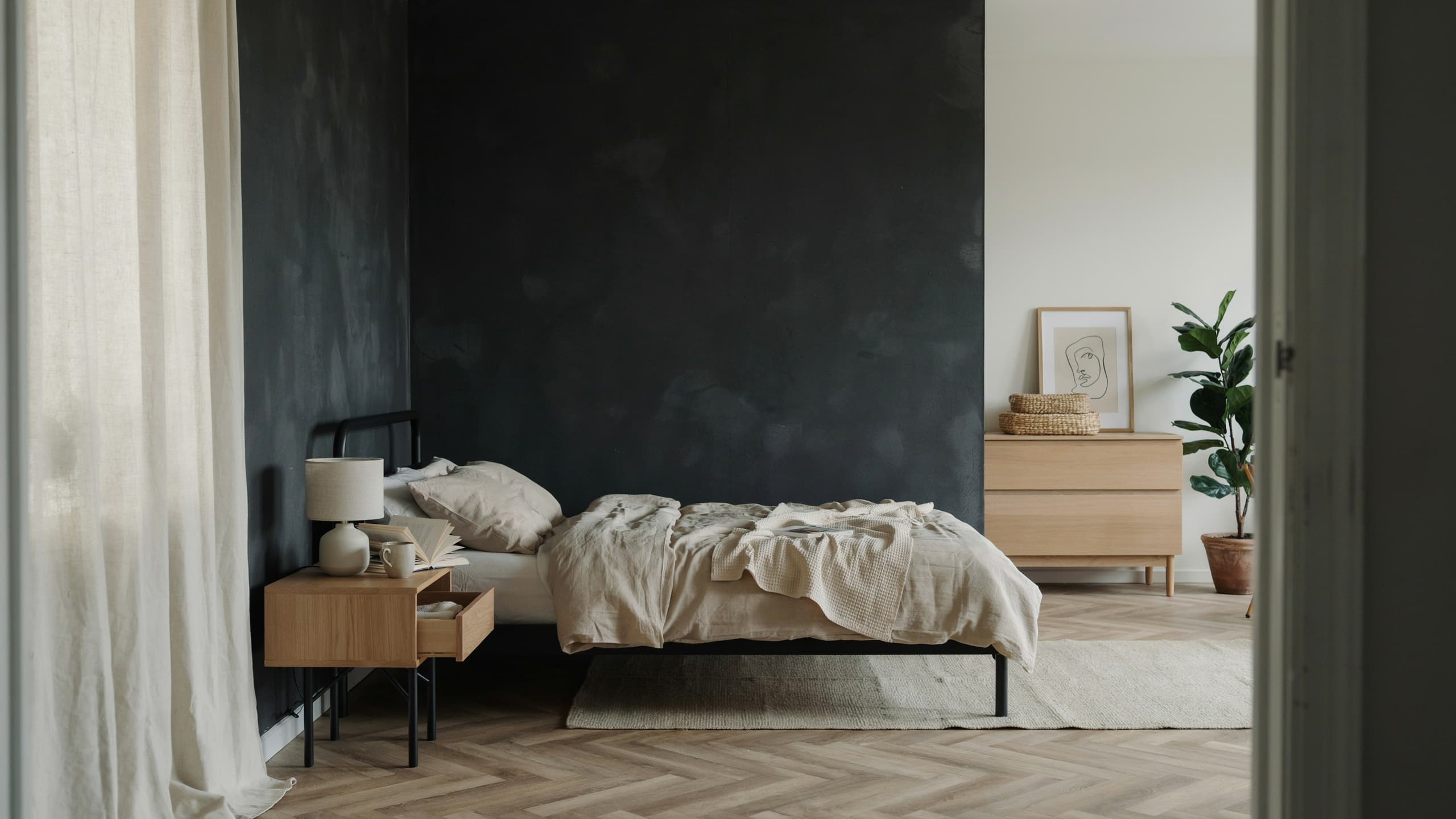 Black Scandinavian bedroom with light wood furniture and neutral decor