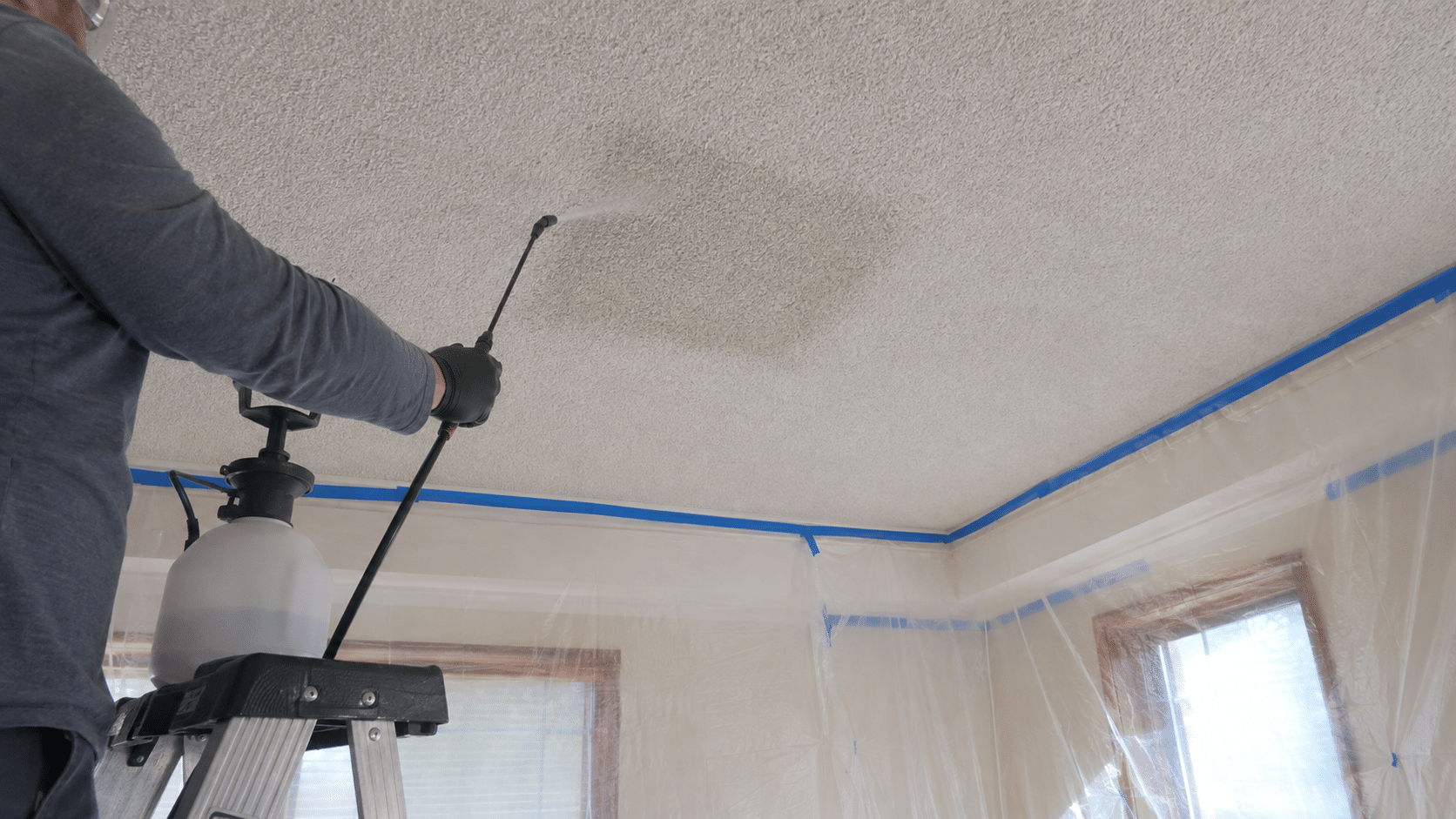 Spraying a popcorn ceiling with water in small sections before removing the texture.