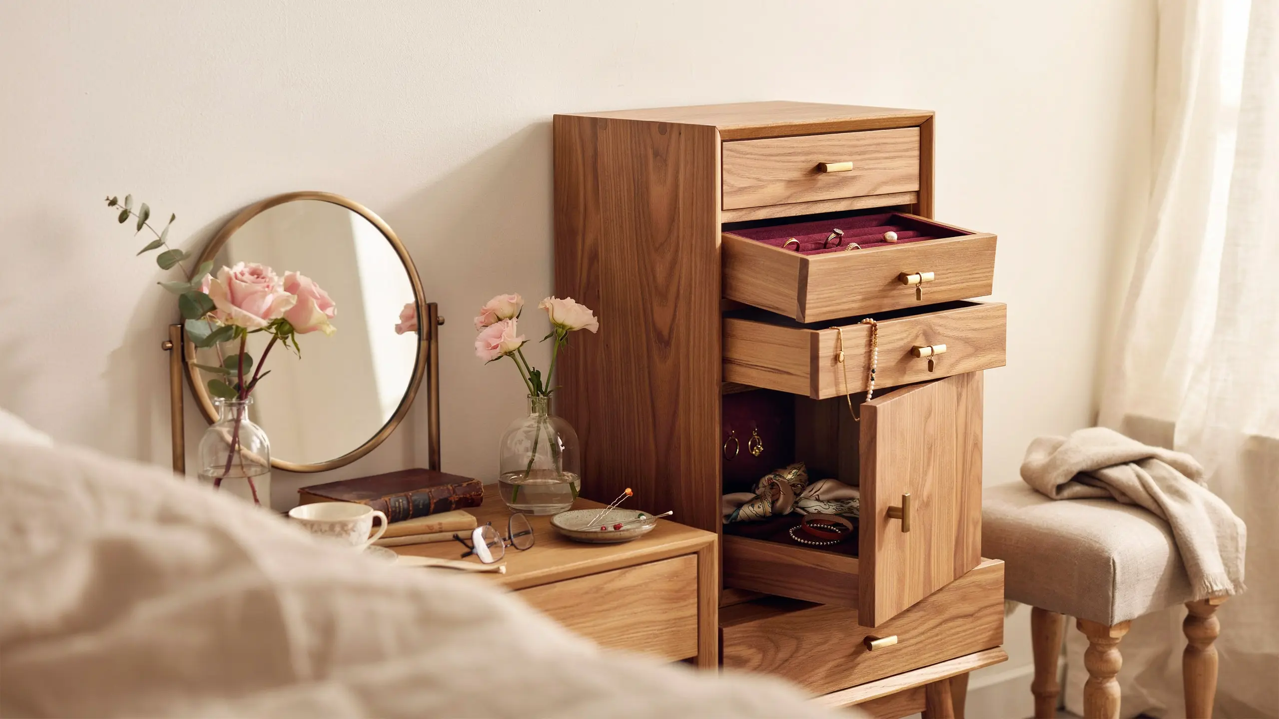 Wooden jewelry armoire with open drawers and storage in a bedroom